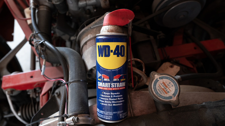 A blue can of WD40 sitting in some engine parts