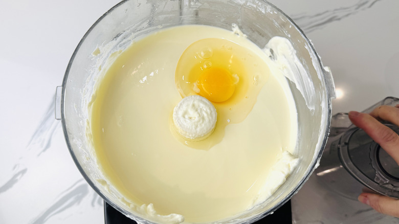 Adding eggs to cheesecake filling in food processor