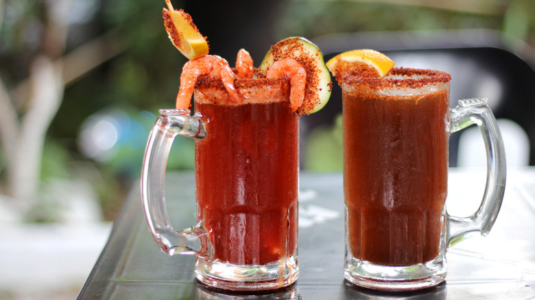 Two micheladas with shrimp and orange slices on the rim