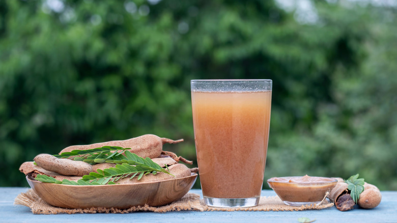 Tamarindo in glass next to tamarind pods