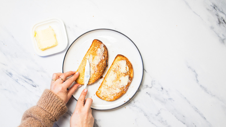 Smearing butter on toasted bread.