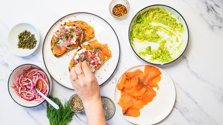 Putting seeds and capers on avocado toast.