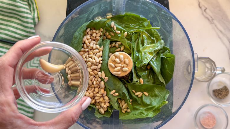 hand adding garlic to food processor