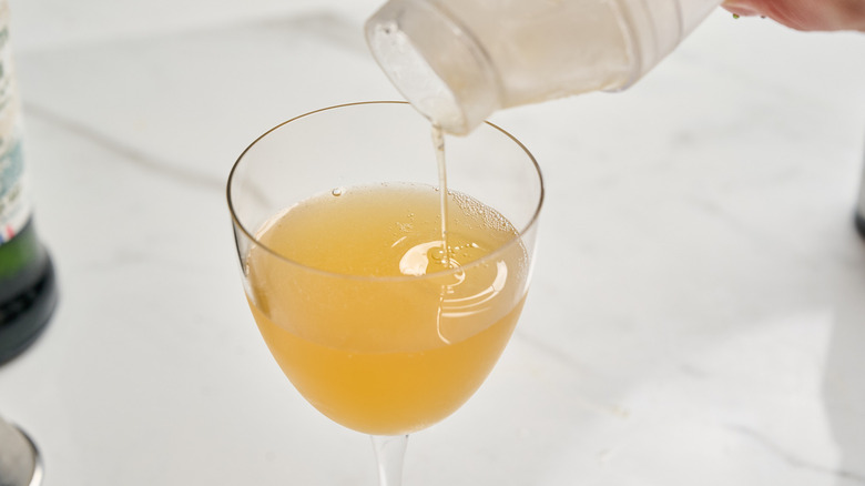 straining cocktail into cocktail glass
