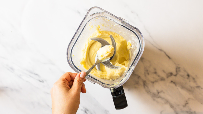 Lifting a spoon out of the blended Dole Whip ice cream in blender.