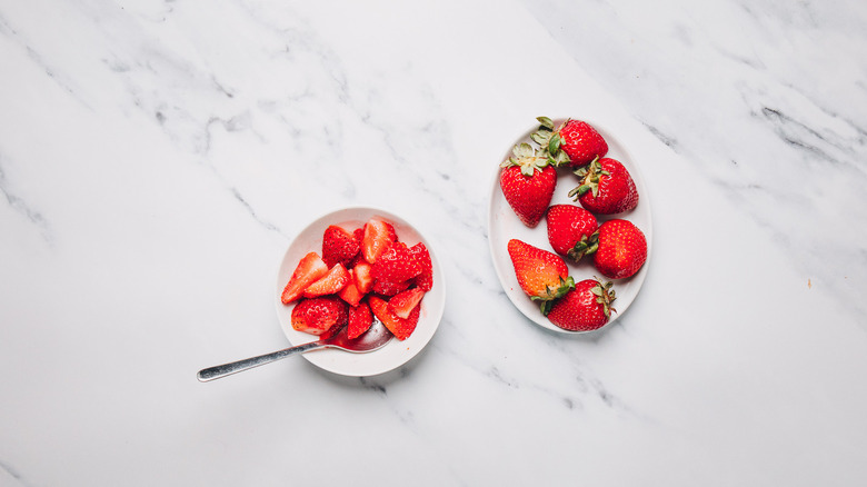 Strawberries with sugar in small bowl besides strawberries.