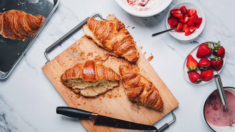 Slicing croissants in half on cutting board.