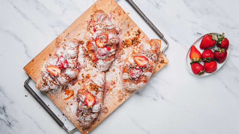 Assembled cheesecake strawberries on cutting board.