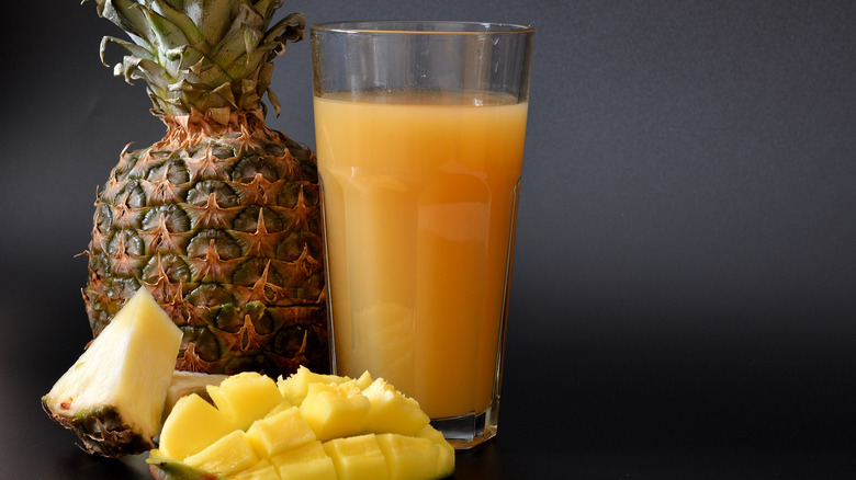 glass of pineapple mango juice with mango and pineapple on the side