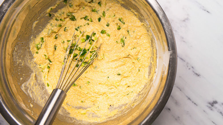 Spicy corn dog muffin batter in bowl with whisk.