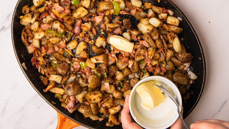 Adding butter to spiced cowboy-style potatoes in pan