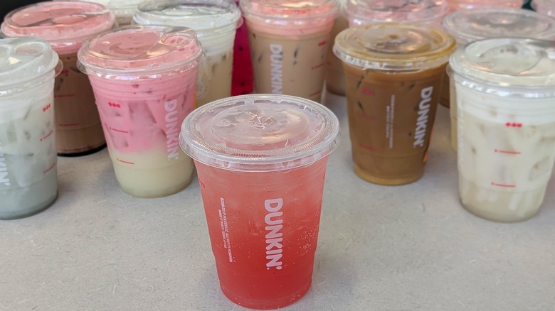 A variety of pink and brown Dunkin' drinks arranged close together on a table