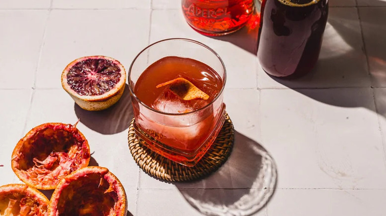 Aerial view of cocktail with blood oranges halved and squeezed off to the side with bottles out of frame.