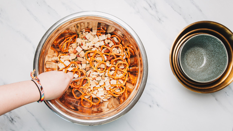 Mixing snack mix ingredients in large bowl.