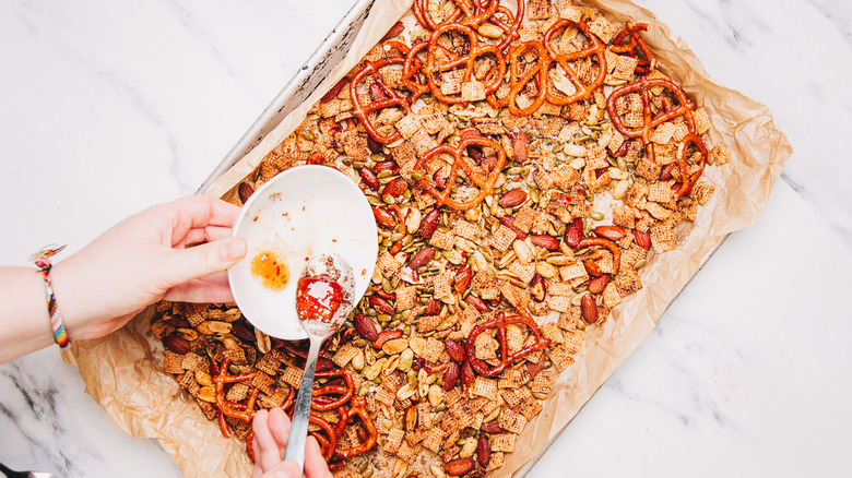 Adding hot honey into savory snack mix.