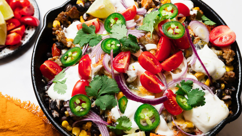 Potato breakfast skillet topped with grape tomatoes, jalapeños, and sour cream