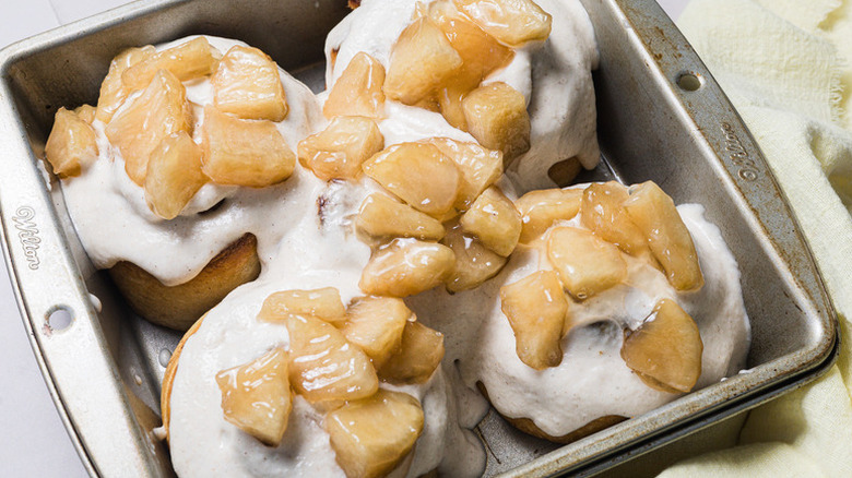 Four iced apple and cinnamon rolls in square baking pan