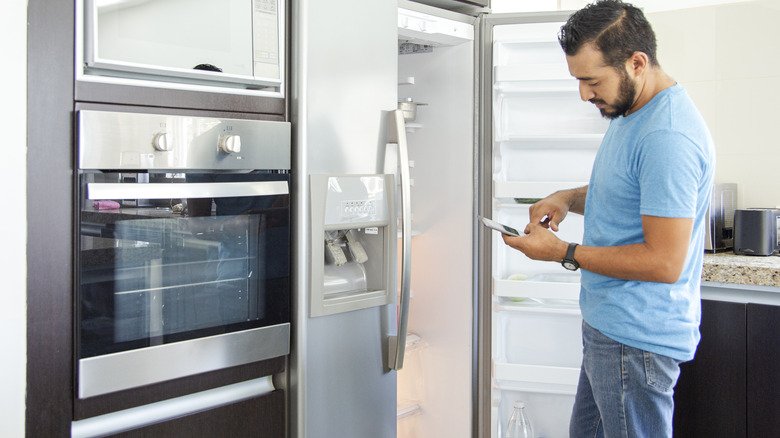 Man standing in front of refrigerator next to a wall oven