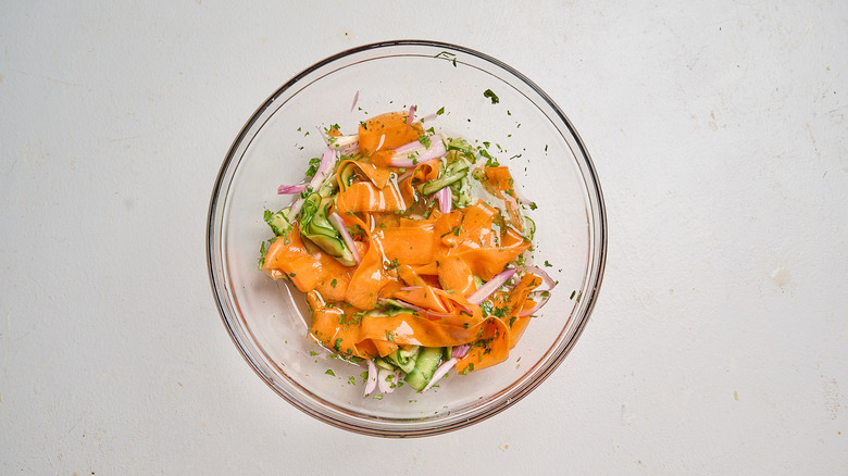 cilantro mixed into bowl with carrot and cucumber