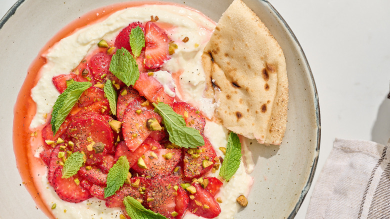 pita scooping feta out of bowl with strawberries