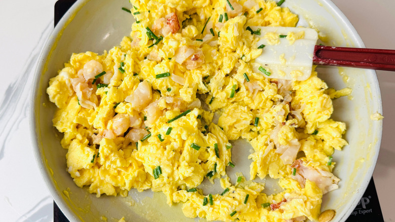 Scrambled eggs, lobster meat, and chives in pan