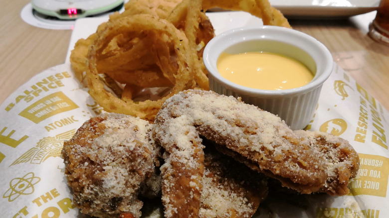 A close up of Wingstop wings, onion rings, and dipping sauce