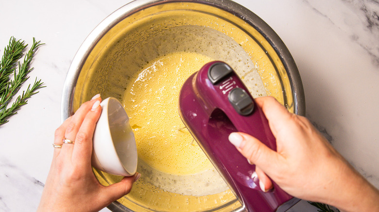 Adding oil while whipping cake batter in bowl.