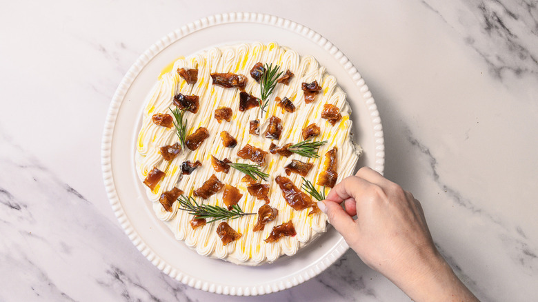 Garnishing gluten-free lemon olive oil cake with rosemary.