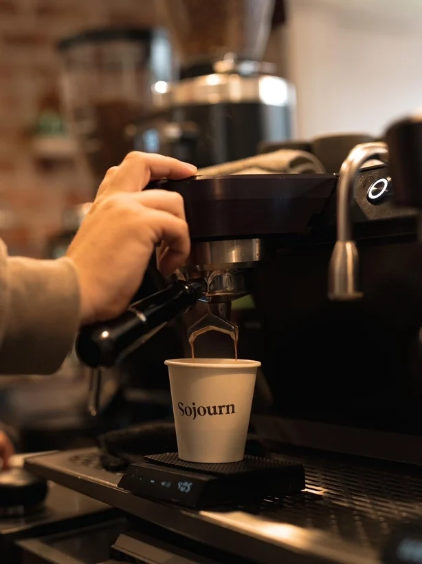 A barista pulling a shot of espresso at a coffee machine