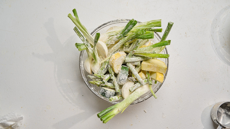 tossing vegetables with flour in a bowl