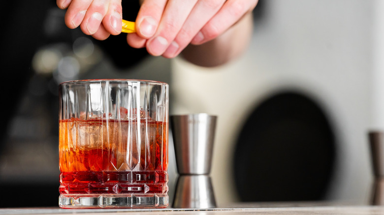 hands squeezing lemon into a cocktail glass