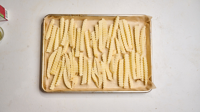 French fries on a sheet tray tossed with oil