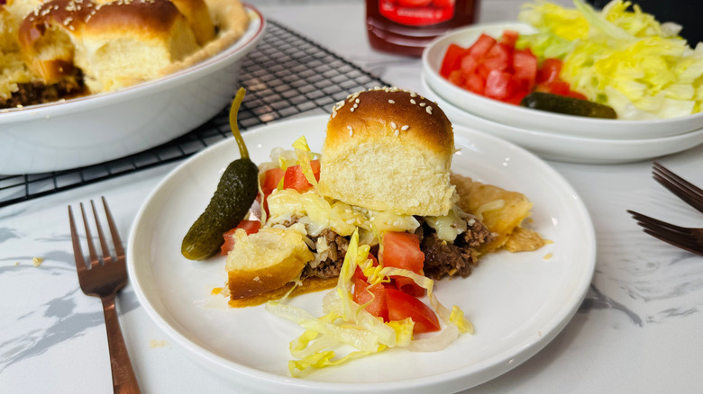 Cheeseburger pie slice with tomato, lettuce, and pickle sides