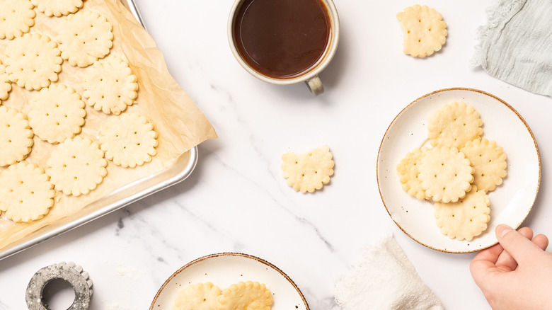 Overhead view of hand placing a plate of shortbread cookies on table.