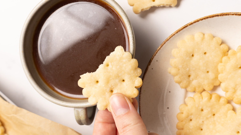 Holding shortbread cookie over coffee.
