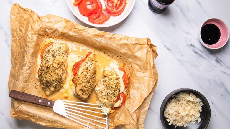 Three Caprese-stuffed chicken breasts on baking sheet
