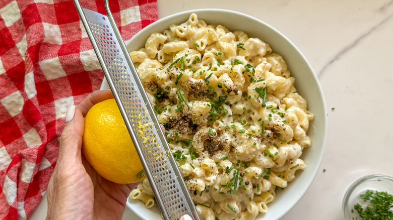 hand zesting lemon over cacio e pepe mac and cheese