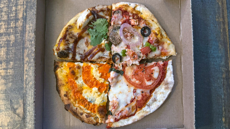one slice each of four different MOD pizzas in a pizza box