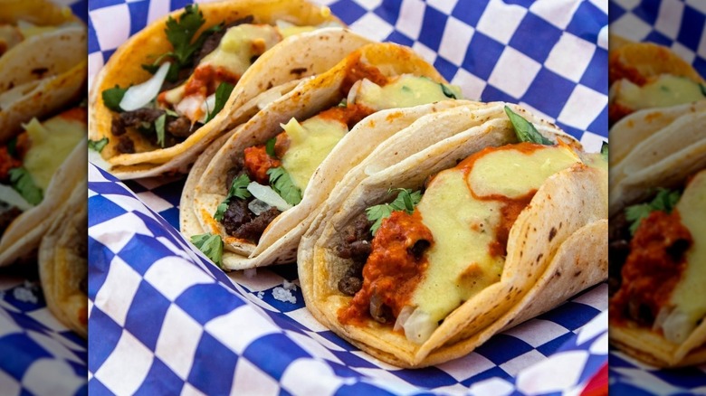 Three tacos served on blue and white paper