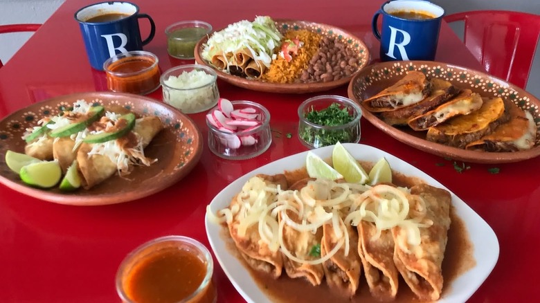 Four plated taco choices on a red table