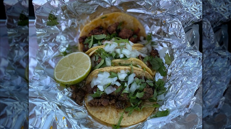 Two tacos with onions placed in tin foil