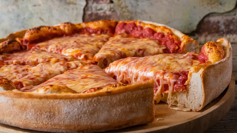 A Chicago-style deep dish pizza is on a cutting board.