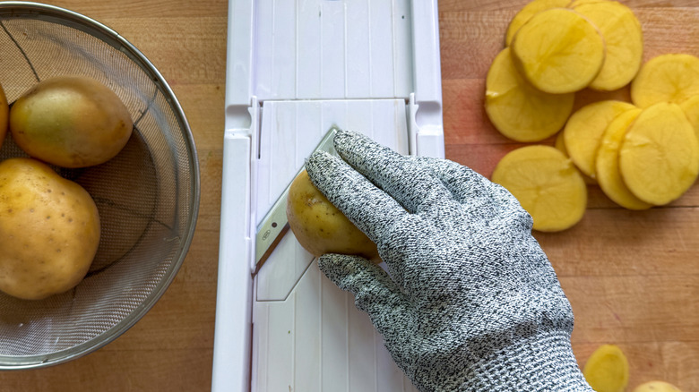 hand slicing potatoes on mandoline