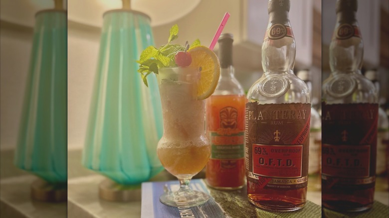 A tiki cocktail on a table next to a half-empty Planteray OFTD rum bottle.