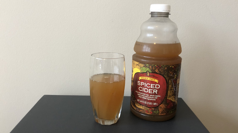 Plastic bottle of Trader Joe's spiced cider with glass full nearby