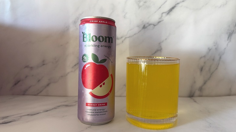 Can of Bloom Crisp Apple next to glass of energy drink on marble surface