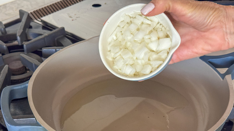 hand adding onion to pan