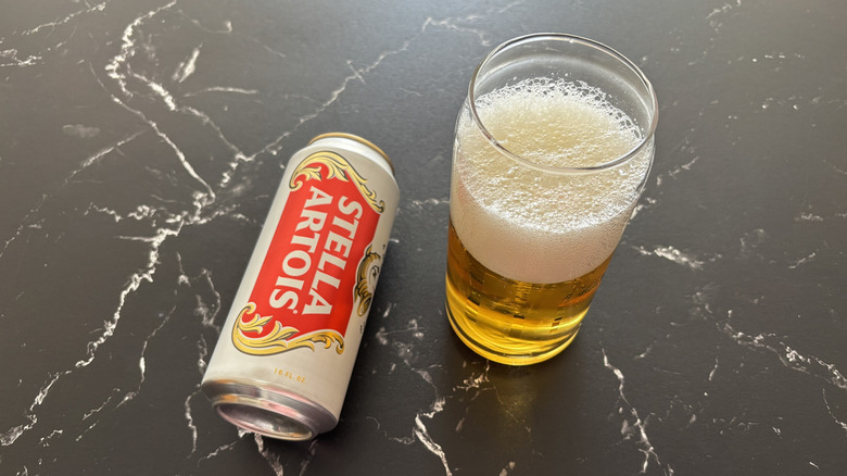 Stella Artois beer can next to glass of beer