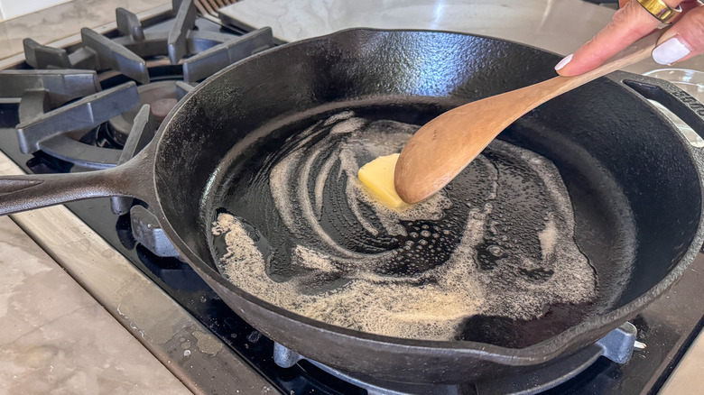 Wooden spoon stirring butter into skillet