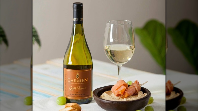 a bottle and glass of of Carmen Gran Reserva Chardonnay white wine with a bowl of hummus